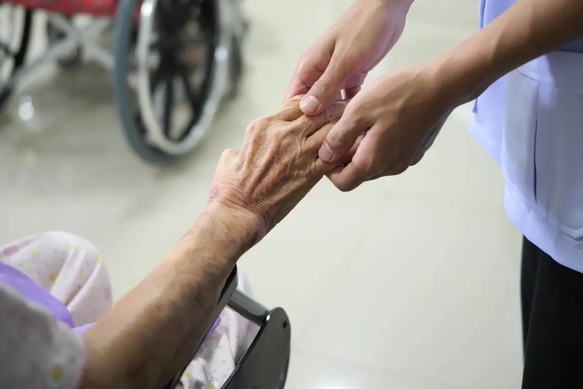 เจ้าหน้าที่จับมือดูแลผู้สูงอายุอย่างใกล้ชิด